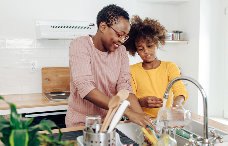 Adult and child washing dishes together